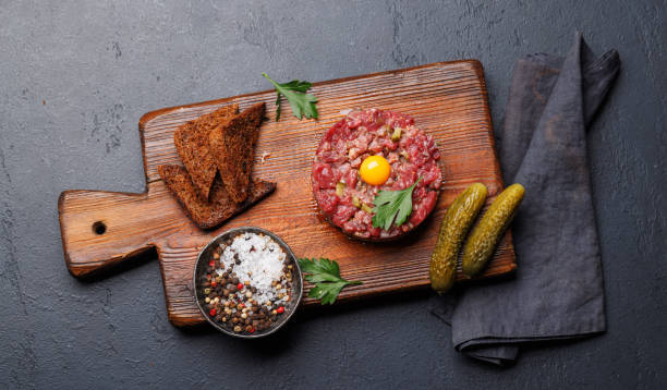 Savory beef tartare with pickled gherkins and brown bread toasts. Flat lay